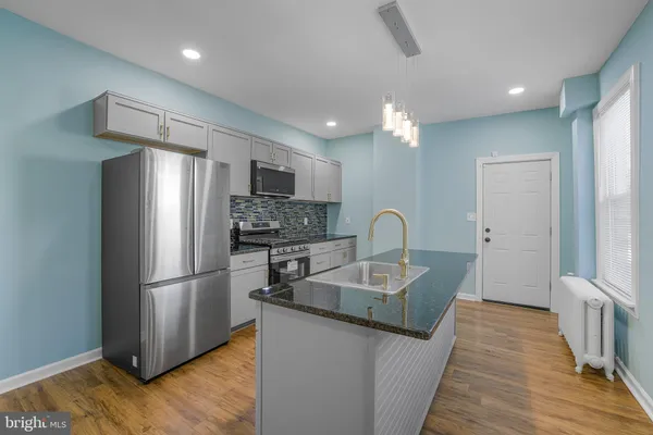 a kitchen with stainless steel appliances granite countertop a refrigerator a sink dishwasher a stove with white countertops and wooden floor