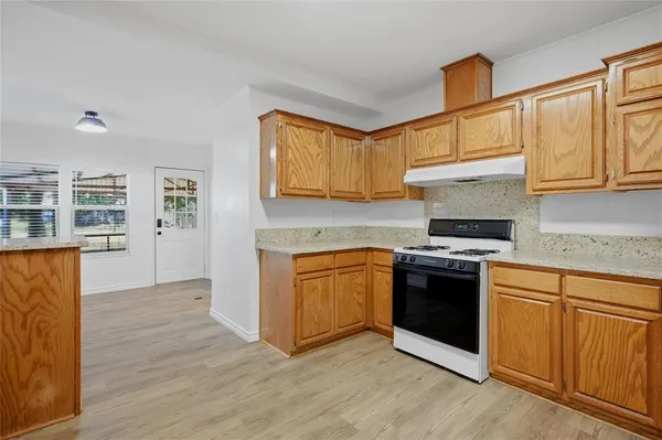 a kitchen with granite countertop wooden cabinets and a stove