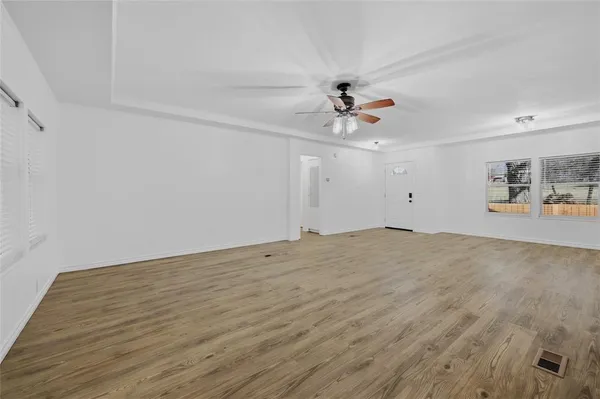a view of a room with wooden floor and ceiling fan