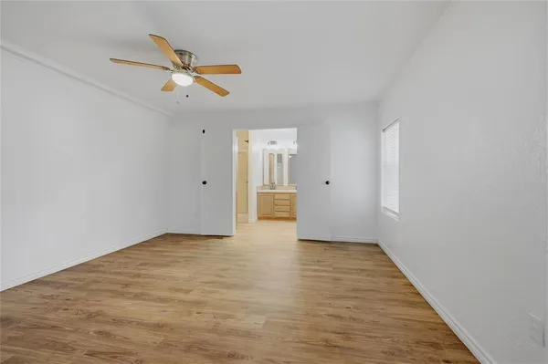 a view of empty room with wooden floor and ceiling fan