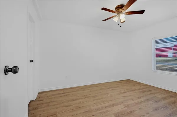 an empty room with a window and a ceiling fan