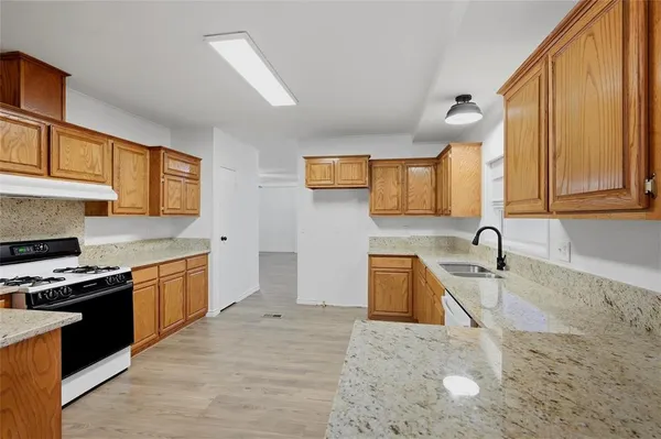 a kitchen with granite countertop a stove sink and cabinets