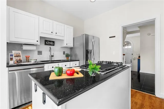 a kitchen with stainless steel appliances granite countertop a stove a sink and white cabinets
