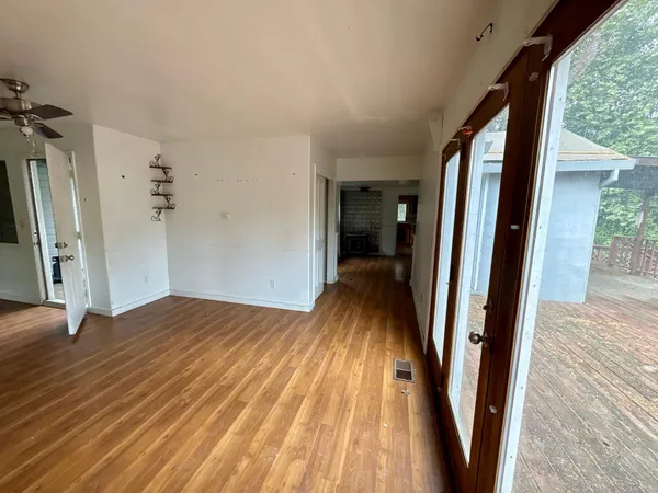 a view of an empty room with wooden floor and a window