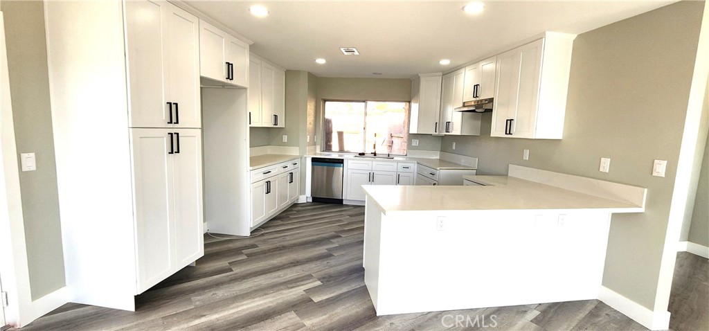 16257 St Timothy Road Apple Valley, CA 92307 - Photo 11 of 28 a kitchen with stainless steel appliances kitchen island granite countertop a refrigerator a sink a stove and white cabinets with wooden floor