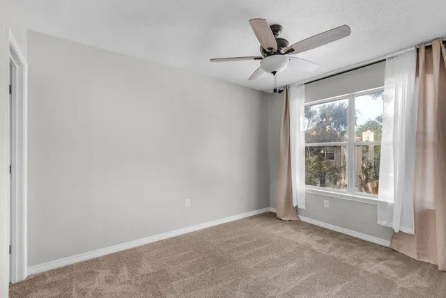 an empty room with windows and ceiling fan