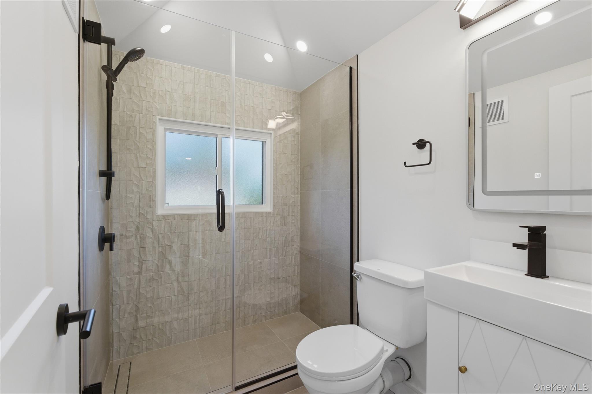 40 Calhoun Avenue New Rochelle, NY 10801 - Photo 29 of 49 Modern bathroom featuring a glass-enclosed shower with matte black fixtures, textured tile surround, and a frosted window