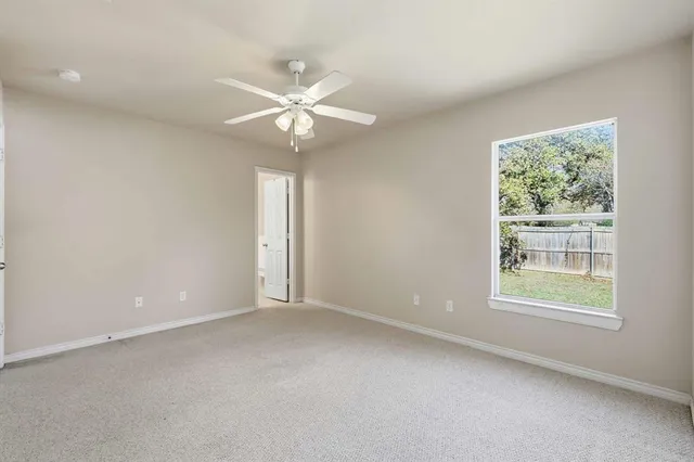 an empty room with a window and a fan