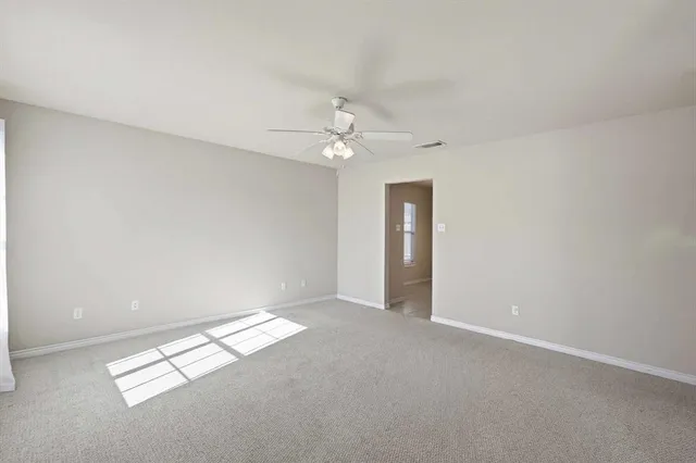 an empty room with chandelier fan and windows