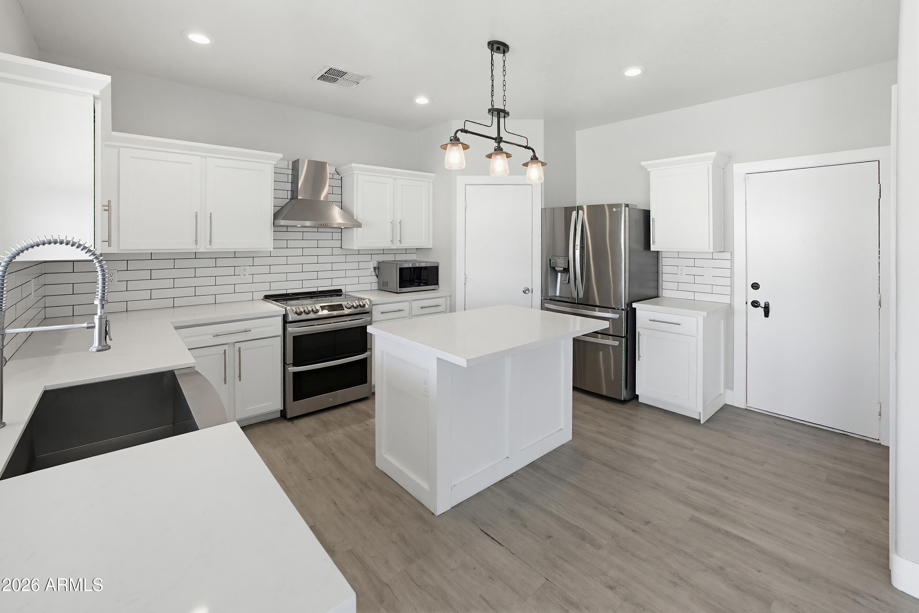 3818 West Carson Road Phoenix, AZ 85041 - Photo 11 of 41 a kitchen with stainless steel appliances kitchen island granite countertop a refrigerator a sink dishwasher a stove and white cabinets with wooden floor