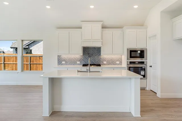 a kitchen with kitchen island granite countertop a stove and a sink