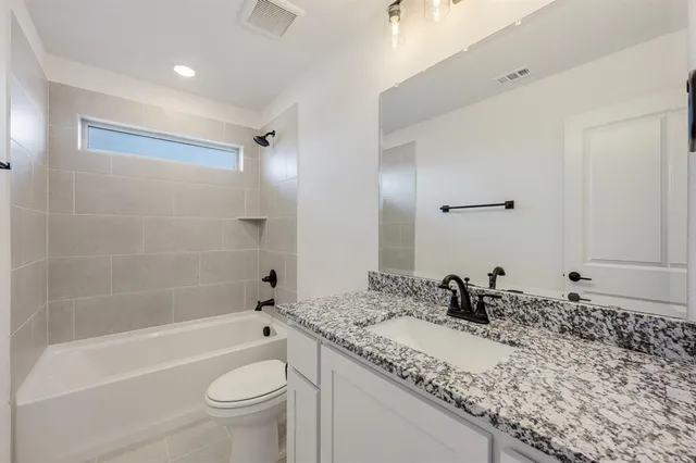 a bathroom with a granite countertop sink a toilet and bathtub