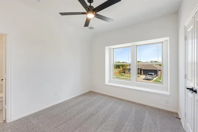 an empty room with a window and a ceiling fan