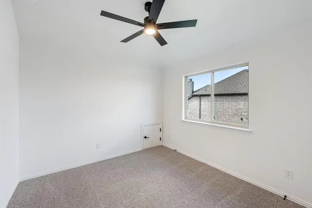 an empty room with a ceiling fan and a window