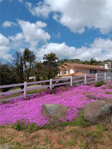 a front view of a house with a lot of flowers and trees