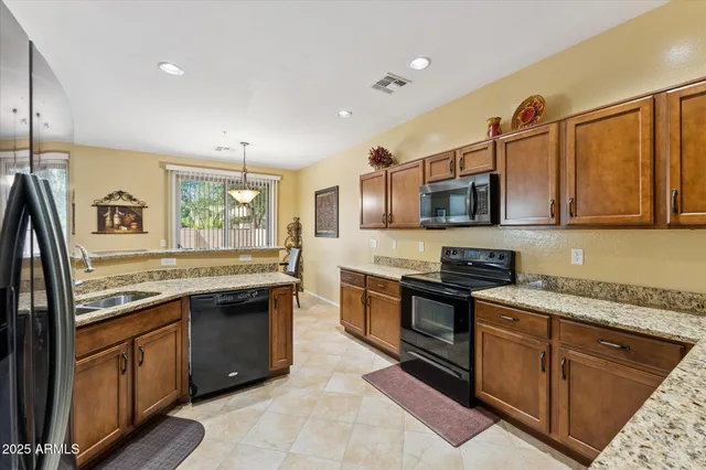 a kitchen with stainless steel appliances granite countertop a stove top oven a sink dishwasher a microwave oven and a refrigerator