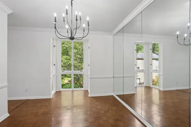 a view of a room with wooden floor chandeliers and kitchen view