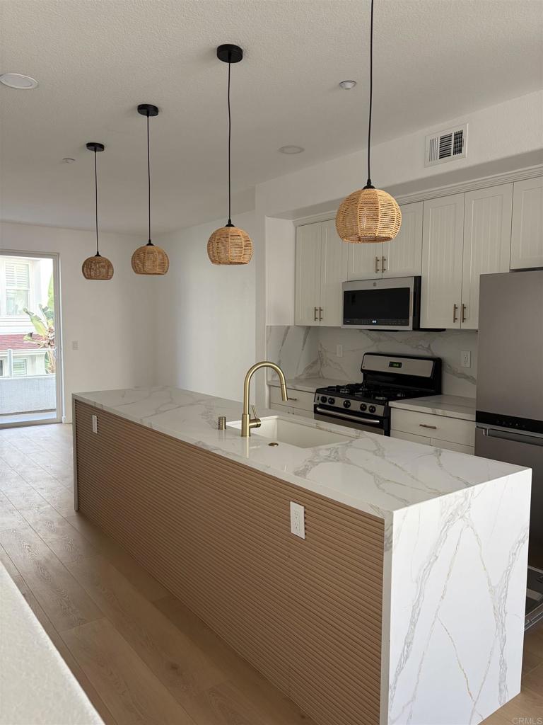 815 Harbor Cliff Way, Unit 239 Oceanside, CA 92054 - Photo 1 of 11 a kitchen with stainless steel appliances granite countertop a sink a stove and a wooden floor