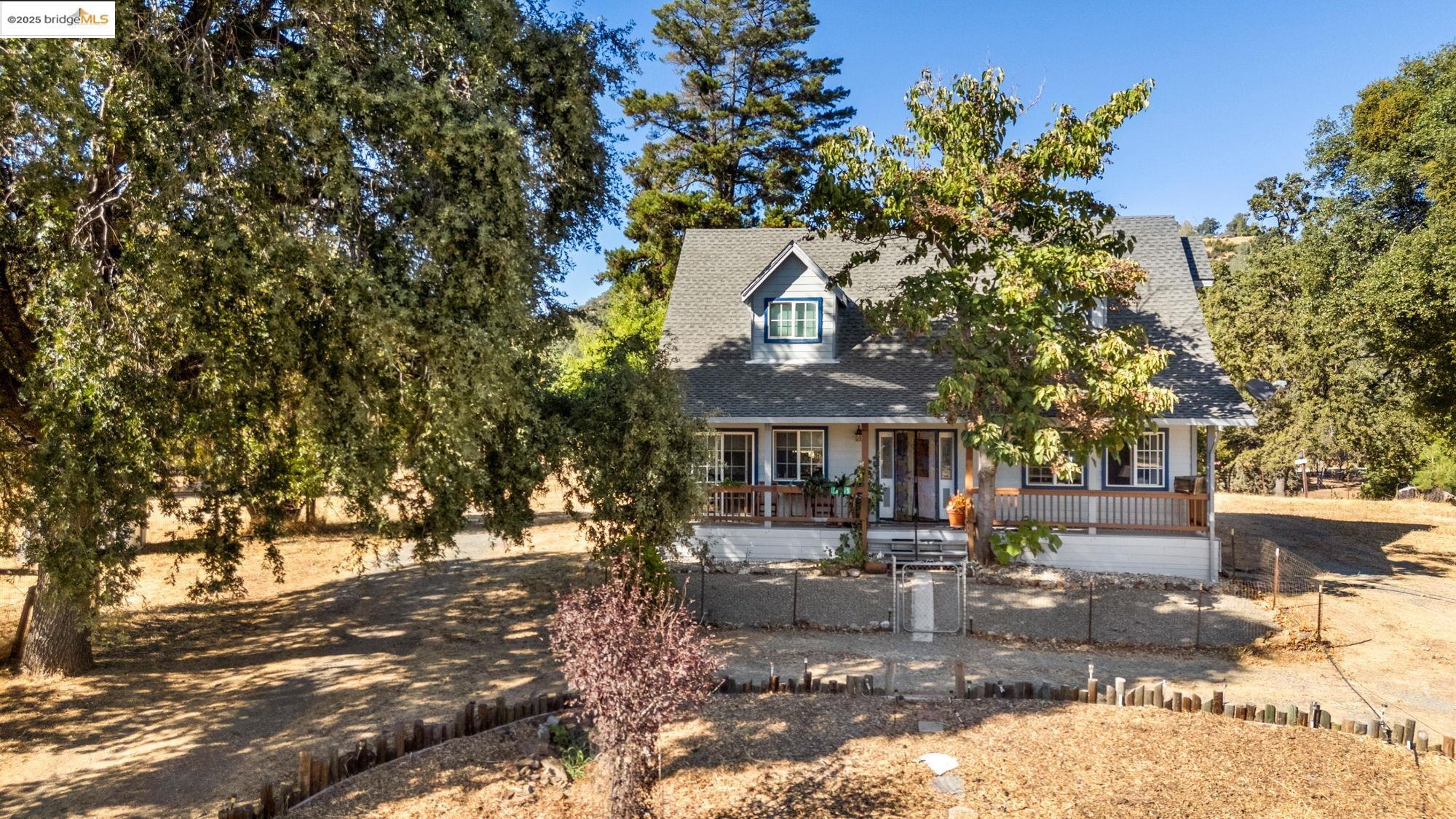 16641 Buckhorn Mountain Road Sonora, CA 95370 - Photo 43 of 44 New england style home with covered porch, a shingled roof, and a fenced front yard