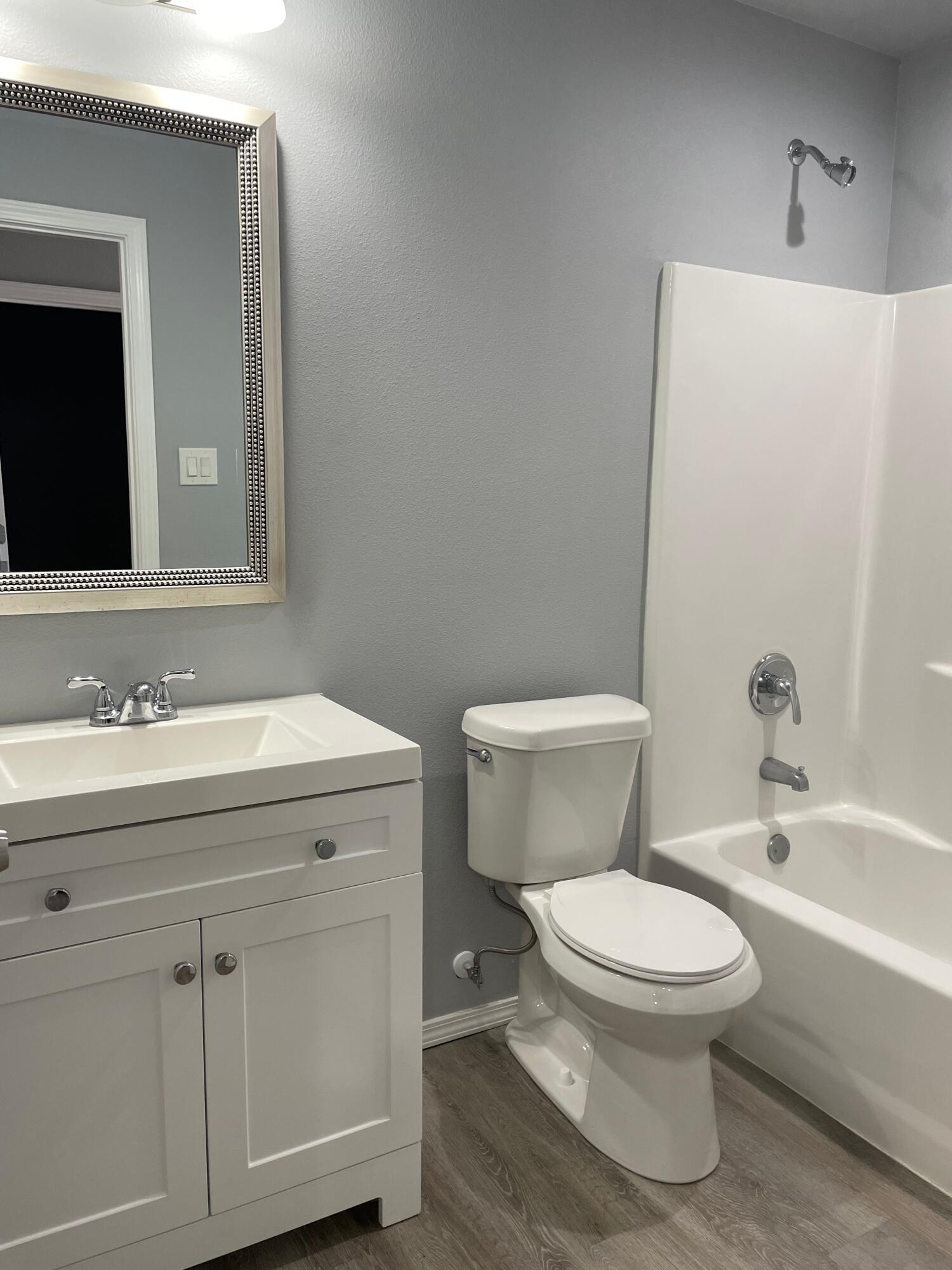1301 North Colton Avenue, Unit A Lubbock, TX 79416 - Photo 2 of 9 a bathroom with a toilet a sink a mirror and bathtub