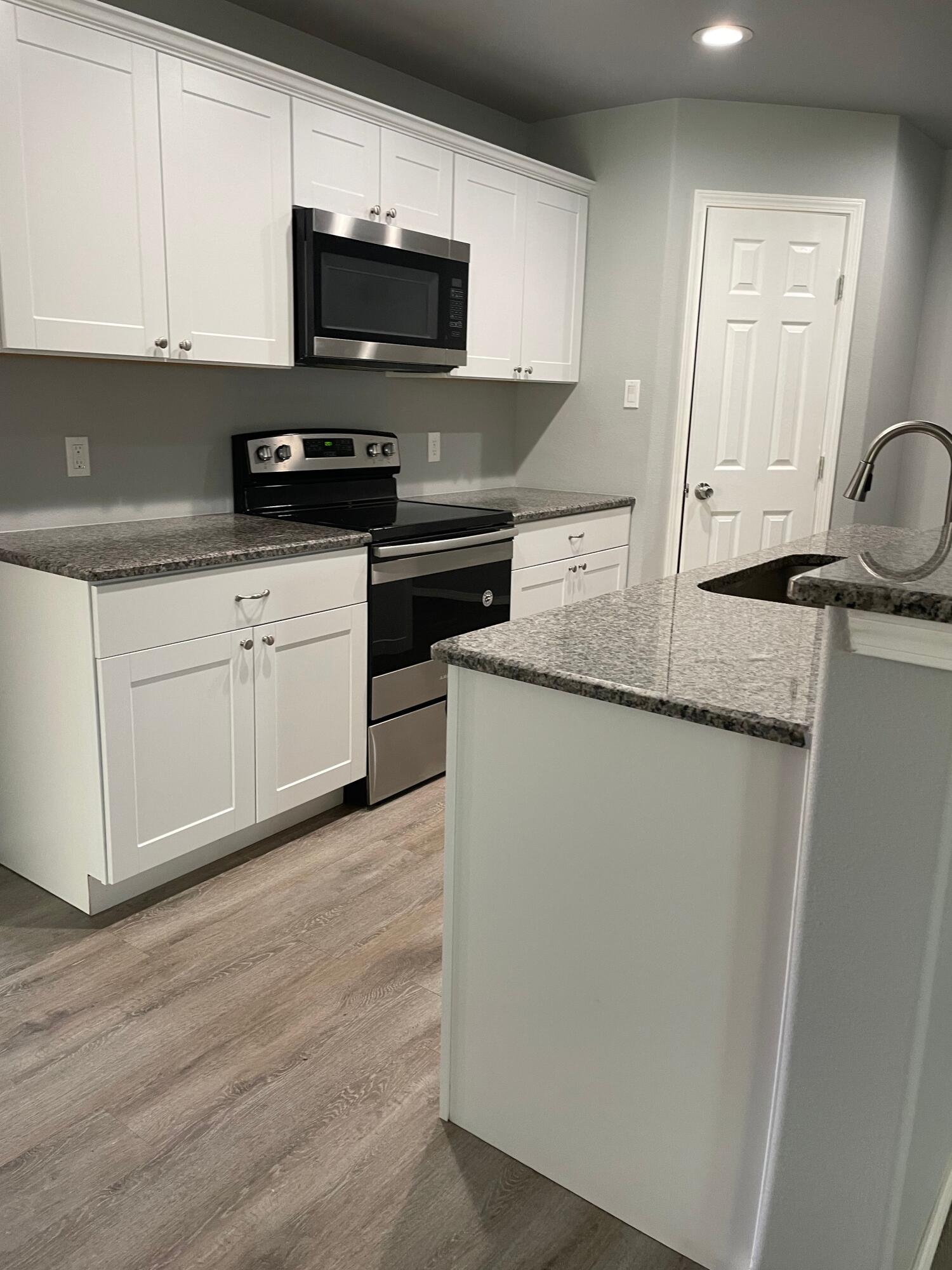 1301 North Colton Avenue, Unit A Lubbock, TX 79416 - Photo 3 of 9 a kitchen with stainless steel appliances granite countertop a stove a sink and a microwave