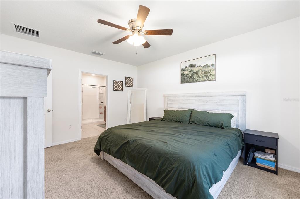 2530 Northeast 42nd Road Ocala, FL 34470 - Photo 23 of 61 a bedroom with a large bed and a chandelier