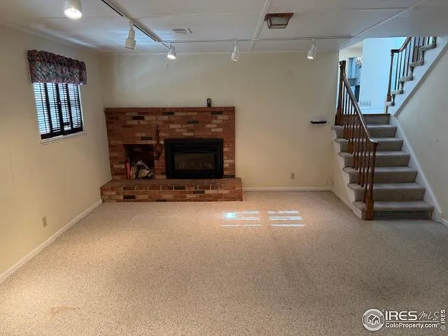 a view of an empty room with stairs and a fireplace