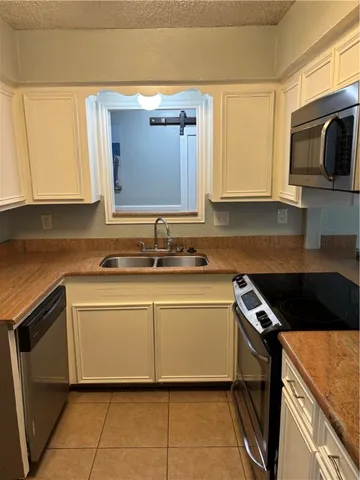 a kitchen with granite countertop a sink stove and microwave