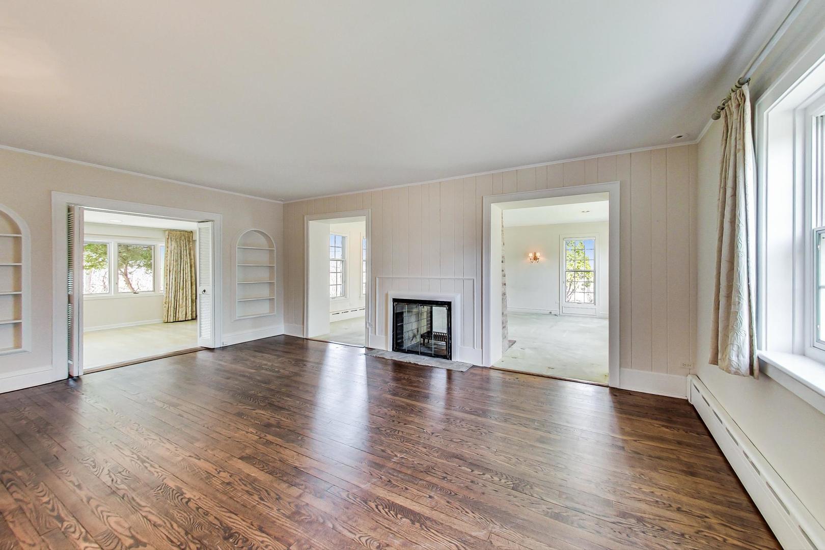 22 Timber Lane Northbrook, IL 60062 - Photo 4 of 41 an empty room with wooden floor fireplace and windows