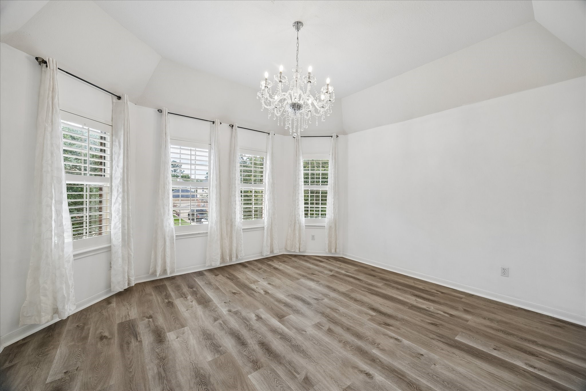 7915 Huddersfield Court Spring, TX 77379 - Photo 30 of 37 Light-filled guest bedroom with engineered flooring, vaulted ceiling, updated floors, elegant chandelier, and multiple windows overlooking the front of the home.