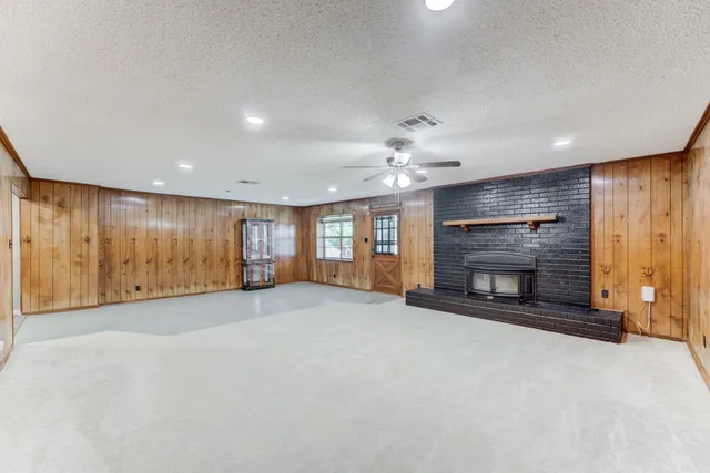 an empty room with fireplace chandelier and windows