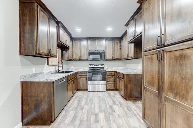 a kitchen with stainless steel appliances granite countertop wooden cabinets a stove top oven a sink and dishwasher