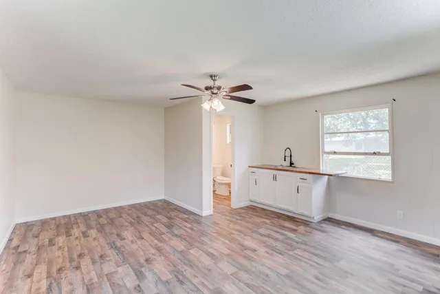 a view of empty room with wooden floor and fan