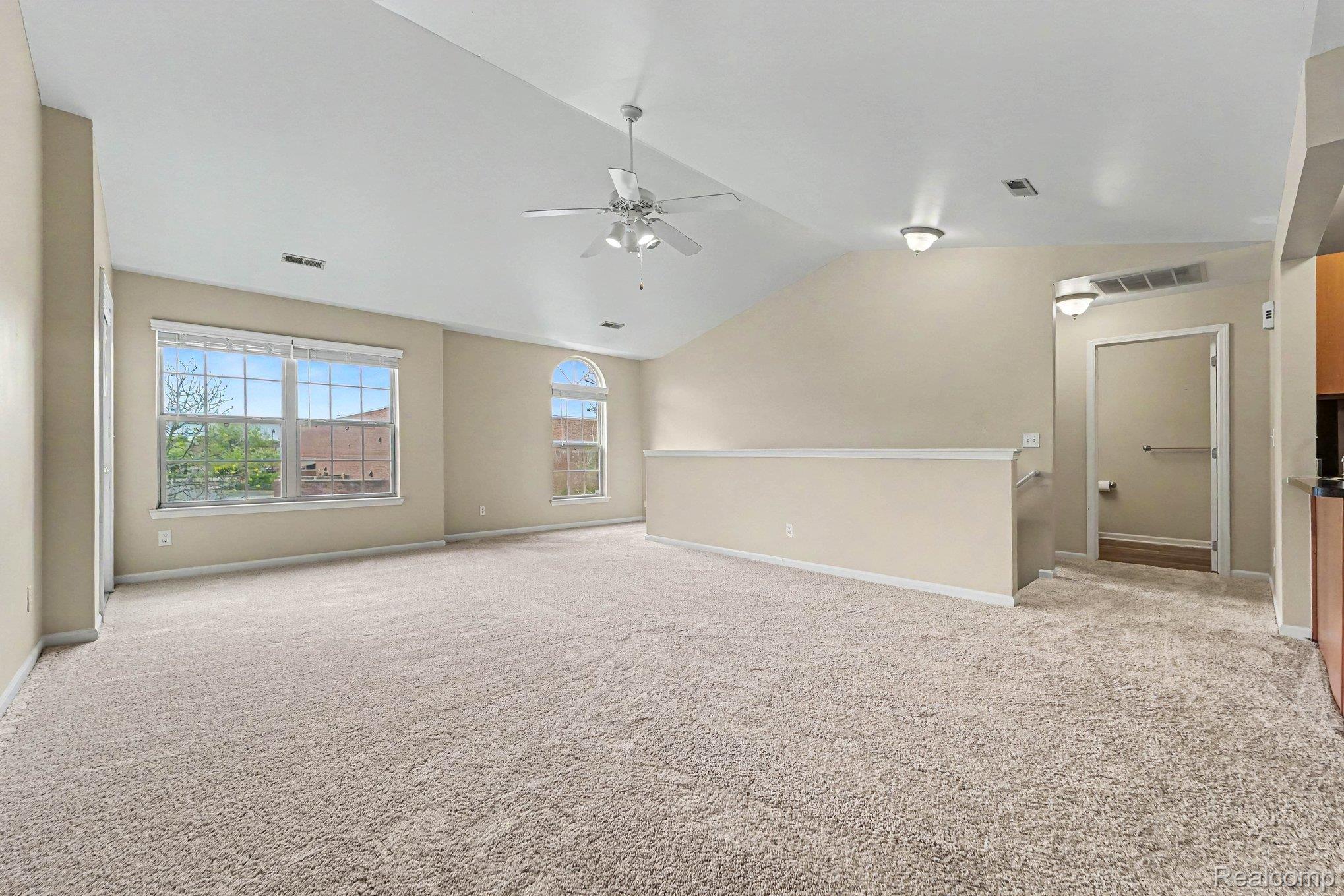 Unfurnished room with light colored carpet, vaulted ceiling, and ceiling fan