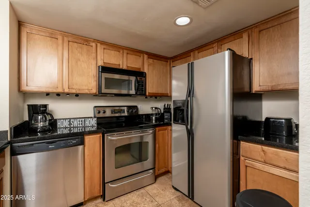 a kitchen with stainless steel appliances granite countertop a stove a refrigerator a sink and dishwasher