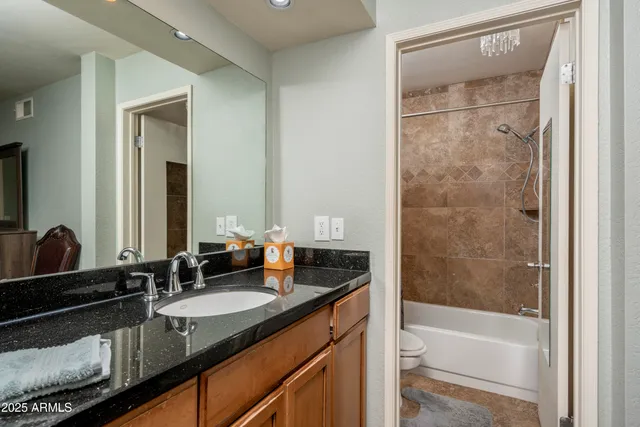 a bathroom with a granite countertop sink a mirror and a bathtub