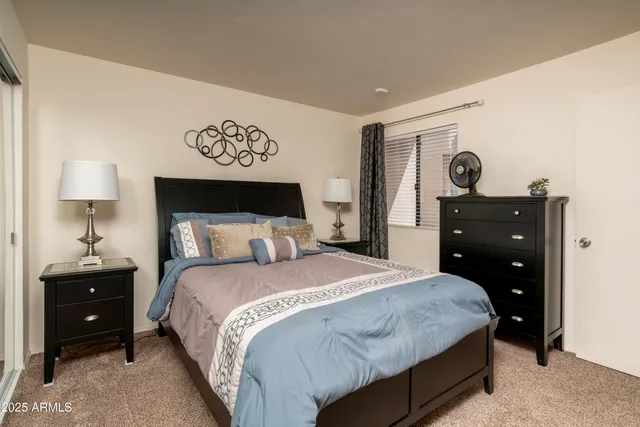 a bedroom with a bed and a lamp on dresser