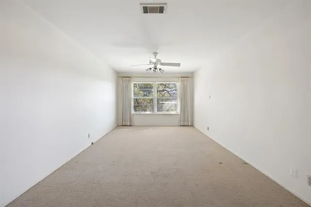an empty room with windows and ceiling fan