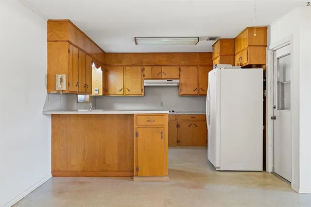 a kitchen with a refrigerator a sink and wooden cabinets