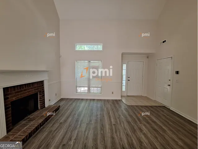an empty room with wooden floor fireplace and windows