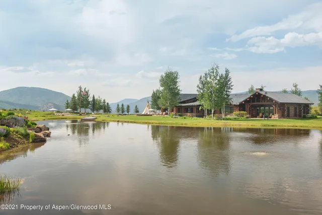 a view of a big house with a big yard and large trees