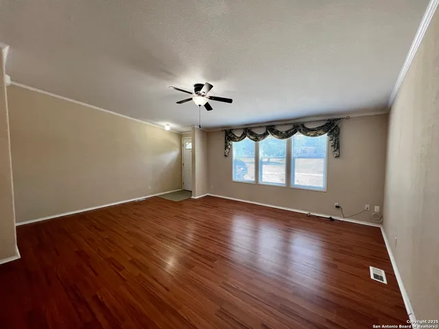 an empty room with wooden floor and windows