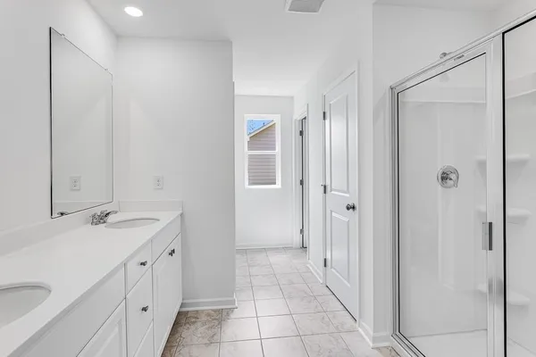 a spacious bathroom with a double vanity sink a mirror and a shower