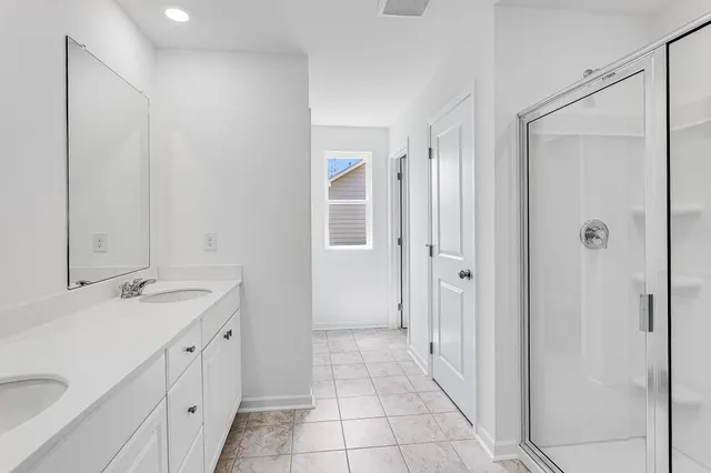 a spacious bathroom with a double vanity sink a mirror and a shower