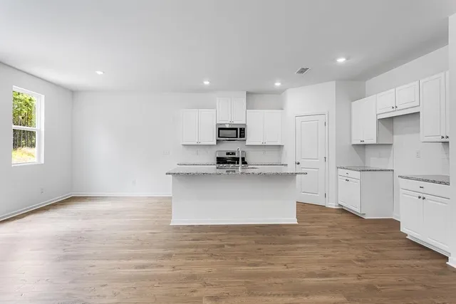 a view of kitchen with granite countertop white cabinets and stainless steel appliances