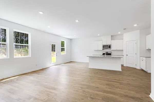 a view of kitchen with kitchen island granite countertop a stove top oven a sink and a dishwasher with wooden floor