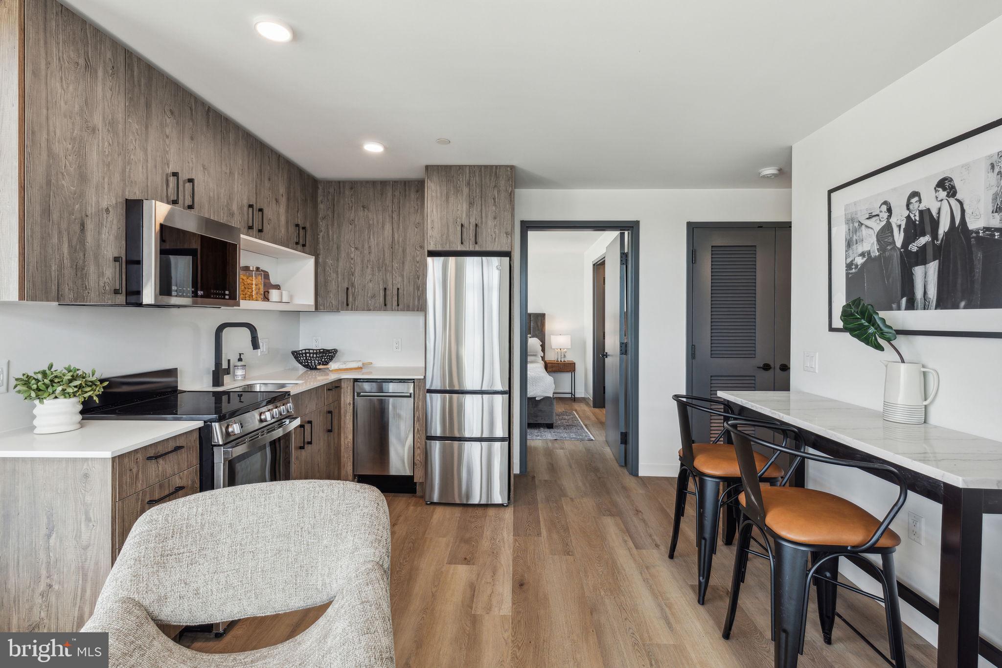 1122 Frankford Avenue, Unit STUDIO A2 Philadelphia, PA 19125 - Photo 33 of 45 a kitchen with stainless steel appliances a dining table chairs refrigerator and sink