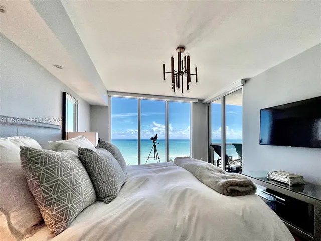 a bedroom with a bed a flat tv screen and a bookshelf