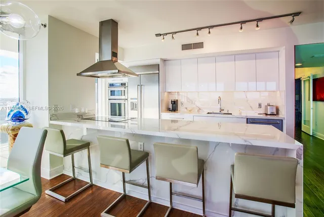 a kitchen with stainless steel appliances a table and chairs in it