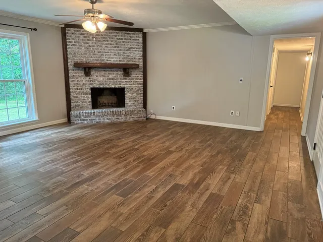 an empty room with wooden floor fireplace and windows